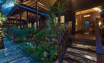 a wooden building with a staircase leading up to the second floor , surrounded by greenery at Coconut Boutique Resort