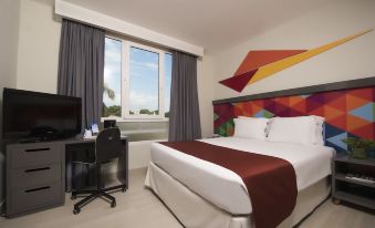 a modern hotel room with a large bed , colorful headboard , and a desk area near a window at Novus Plaza Hodelpa