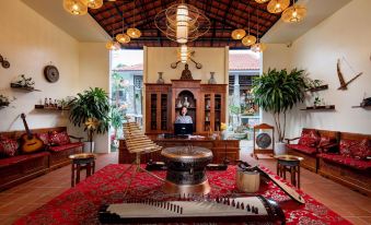 a room with a red rug , wooden furniture , and various musical instruments on the floor at Bai Dinh Garden Resort & Spa