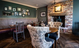 a cozy dining room with two chairs and a table , along with a fireplace in the background at The Saracens Head