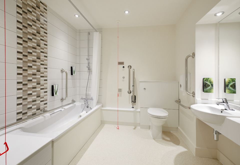 a modern bathroom with white walls , a bathtub , and a walk - in shower , along with some toiletries on the counter at Premier Inn Fareham