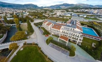 aerial view of a large white building with a blue pool in the middle of a parking lot at Hotel President Solin