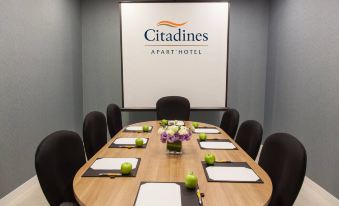 a conference room with a large table , black chairs , and a screen displaying the citadines logo at Citadines DPulze Cyberjaya
