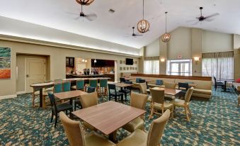 a spacious , well - lit room with wooden tables and chairs , a bar area , and hanging lights at Homewood Suites by Hilton Tampa-Port Richey
