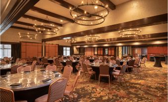 a large , well - lit banquet hall with multiple dining tables and chairs set up for an event at The Craftsman Inn & Suites
