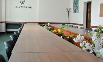 a long wooden table with a vase of flowers in the center and chairs arranged around it at Vila Verde