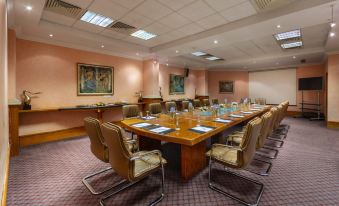 a conference room with a large wooden table surrounded by chairs and papers on the table at GrandResort by Leonardo Hotels