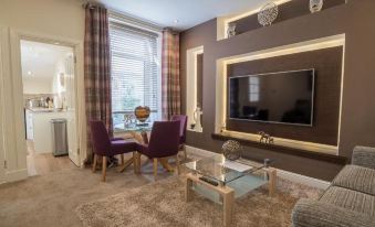 a cozy living room with a large flat - screen tv mounted on the wall , surrounded by comfortable furniture at Carmel Apartments