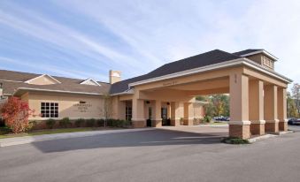 a large building with a brown roof and columns is shown from the entrance at Homewood Suites by Hilton Rochester - Victor