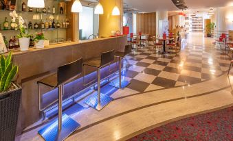 a modern bar area with a checkered floor , multiple chairs , and blue lighting , surrounded by red tables and a checkered floor at Ibis Firenze Nord Aeroporto