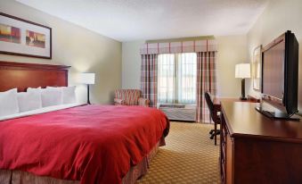 a hotel room with a red bed , curtains , and a desk , along with other furniture such as a bed , nightstands , and a at Country Inn & Suites by Radisson, Rock Falls, IL