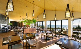 a modern restaurant with wooden floors , large windows offering views of the ocean , and multiple dining tables at Castaways Resort