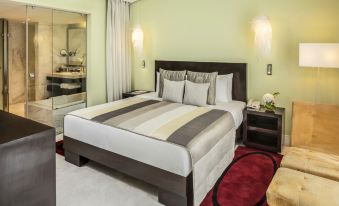 a large bed with a striped comforter and multiple pillows is in a room with green walls at The Park Chennai