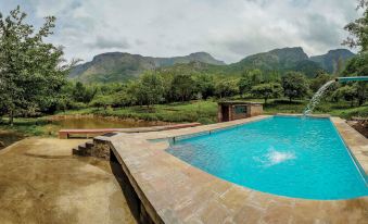 a large outdoor swimming pool surrounded by lush greenery and mountains , creating a serene and picturesque setting at Jungle Hut