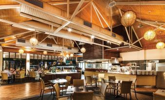 a large , well - lit restaurant with wooden floors , high ceilings , and various dining tables and chairs at Travelodge Resort Darwin