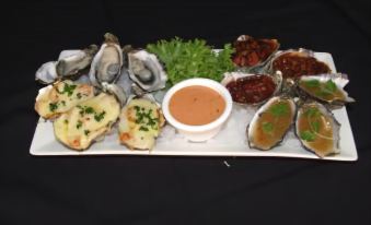 a plate of oysters and a dipping sauce , accompanied by herbs and a small bowl of sauce at Streaky Bay Hotel Motel