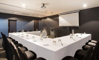 a conference room set up for a meeting , with chairs arranged in a semicircle around a long table at Gambaro Hotel Brisbane