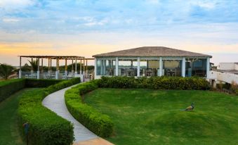 a white building surrounded by a lush green lawn , with a pathway leading up to it at Serena Beach Resort