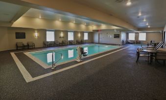 a large indoor swimming pool with a glass door and several chairs around the edge at Hampton Inn Billings