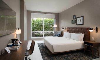 a modern hotel room with a large bed , white bedding , and a view of trees outside the window at Four Points by Sheraton Puntacana Village