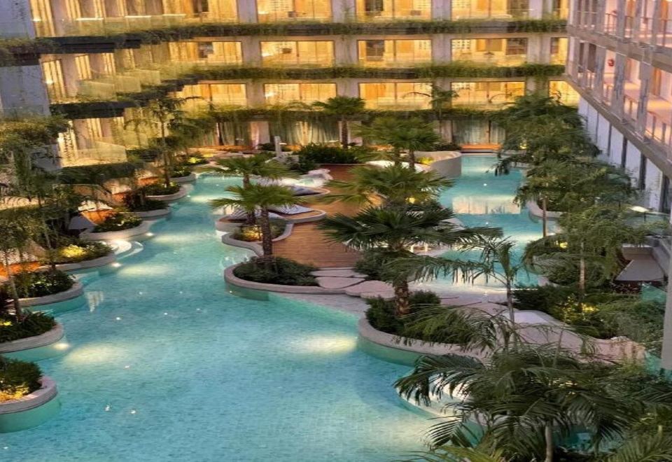 An aerial view reveals a spacious swimming pool at the center, encircled by lush trees and foliage at Panwaburi Beachfront Resort