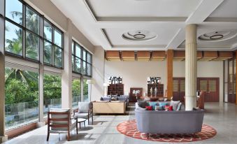 a spacious , well - lit living room with high ceilings , large windows , and various seating options such as couches , chairs , and benches at Sheraton Kosgoda Turtle Beach Resort