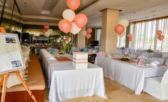 "a room with tables set up for a party , adorned with balloons and flowers , under the theme of "" ceremony .""." at E-Hotel Larnaca Resort & Spa