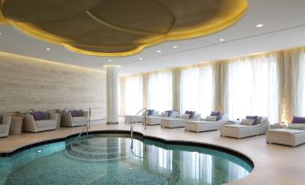 a luxurious indoor pool area with a circular design , white couches , and large windows providing natural light at Waldorf Astoria Berlin