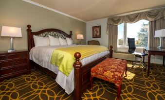 a large bed with a yellow blanket and wooden headboard is in a room with a patterned carpet at Auberge Gisele's Inn