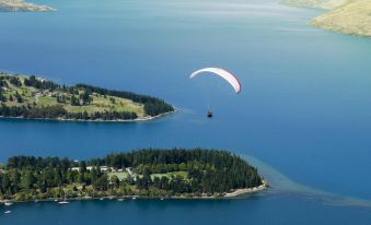 a person is paragliding over a body of water with an island in the background at Lakeside Motel