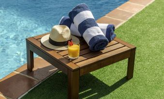 a wooden table with a striped towel , sunglasses , and a drink on it is placed next to a swimming pool at Novotel Sydney Darling Harbour