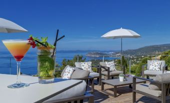 a luxurious outdoor terrace with a dining table , umbrellas , and chairs , offering a breathtaking view of the sea at Hotel la Villa Douce