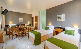 a hotel room with two beds , each bed having green and white linens , a dining table , chairs , and a bathroom at Infinity Copacabana, Ex-APA Hotel