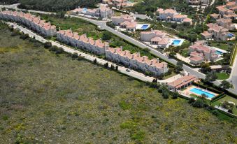 aerial view of a residential area with multiple houses , some of which have red - tiled roofs , situated on a hillside at Martinhal Sagres Beach Family Resort Hotel