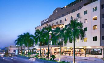 a large hotel building surrounded by palm trees , with a road leading up to it at Aston Karimun City Hotel