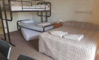 a small room with two beds , one of which is a bunk bed , and a desk at Monto Colonial Motor Inn