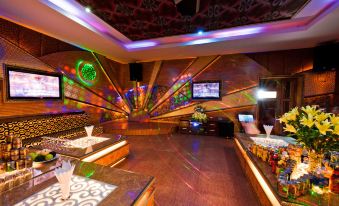 a well - lit , colorful nightclub with multiple televisions and various seating options , giving it an inviting atmosphere at Muong Thanh Dien Chau Hotel