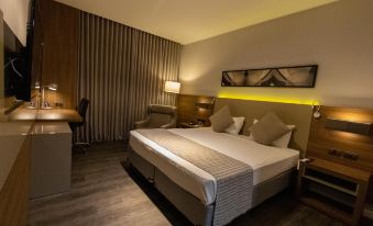 a large bed with a white and gray comforter is in the middle of a room with wooden floors at JL Hotel by Bourbon