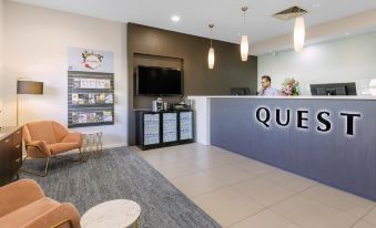 "a modern hotel reception area with a gray and blue checkered floor , white walls , and large letters spelling "" quatres "" on the counter" at Quest Werribee