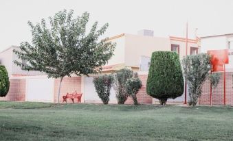 a house with a large tree in front of it and a red bench in the foreground at La Esperanza