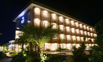 a large hotel building lit up at night , surrounded by palm trees and other plants at Mexolie Hotel