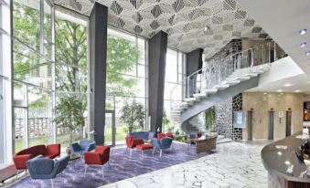 a modern hotel lobby with a large atrium , multiple seating areas , and a spiral staircase at Hotel Continental