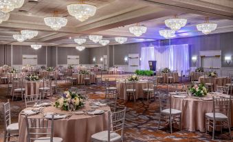 a large banquet hall with tables and chairs set up for a formal event , possibly a wedding reception at Marriott Boston Quincy