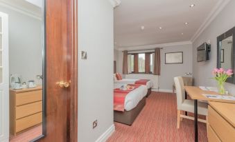 a hotel room with two beds , a dining table , and a door leading to the bathroom at Best Western Bradford Guide Post Hotel