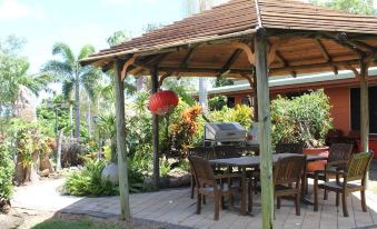 a wooden gazebo with a table and chairs set up for outdoor dining , surrounded by lush greenery at Cooktown Motel