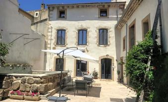a courtyard with a stone patio surrounded by various outdoor furniture , including chairs , tables , and umbrellas at La Bastide