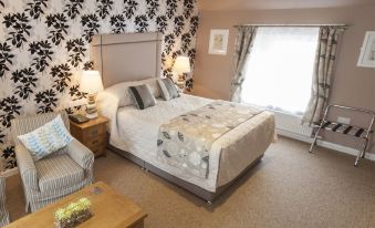 a cozy bedroom with a large bed , a chair , and a tv . also a dining table in the room at The Commercial Hotel