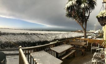 a snow - covered deck with a view of the ocean and palm trees , as well as a dining table and chairs at Breakers