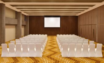 a conference room with rows of white chairs arranged in a semicircle , and a projector screen mounted on the wall at Aloft New Delhi Aerocity