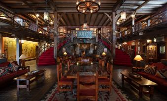 a large room with wooden furniture and a staircase leading to an upper level , surrounded by red rugs at Hotel El Rancho